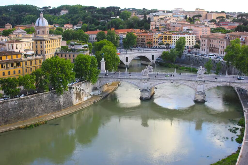 Rome cityscape with bridges over a river, featuring architecture and green trees. boat tour hop on hop off